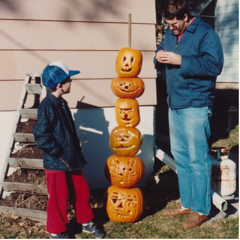 RNL graphic designer Shannon Blazek as a child standing next to a stack of jack o' lanterns