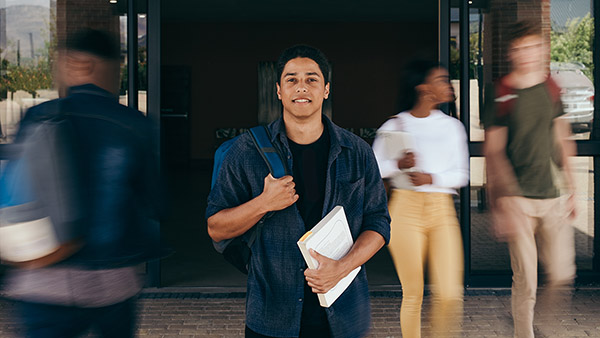 Blog on University Families and the Student Experience: Image of a male college student with blurred students behind him