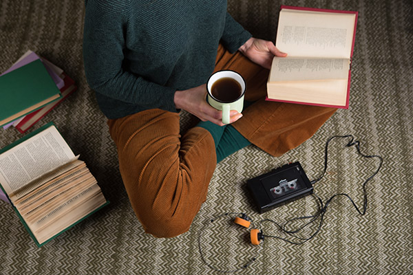 Blog: 30 Years of Assessing Student Satisfaction, image of student sitting on floor reading a book, drinking coffee, and listening to a cassette player